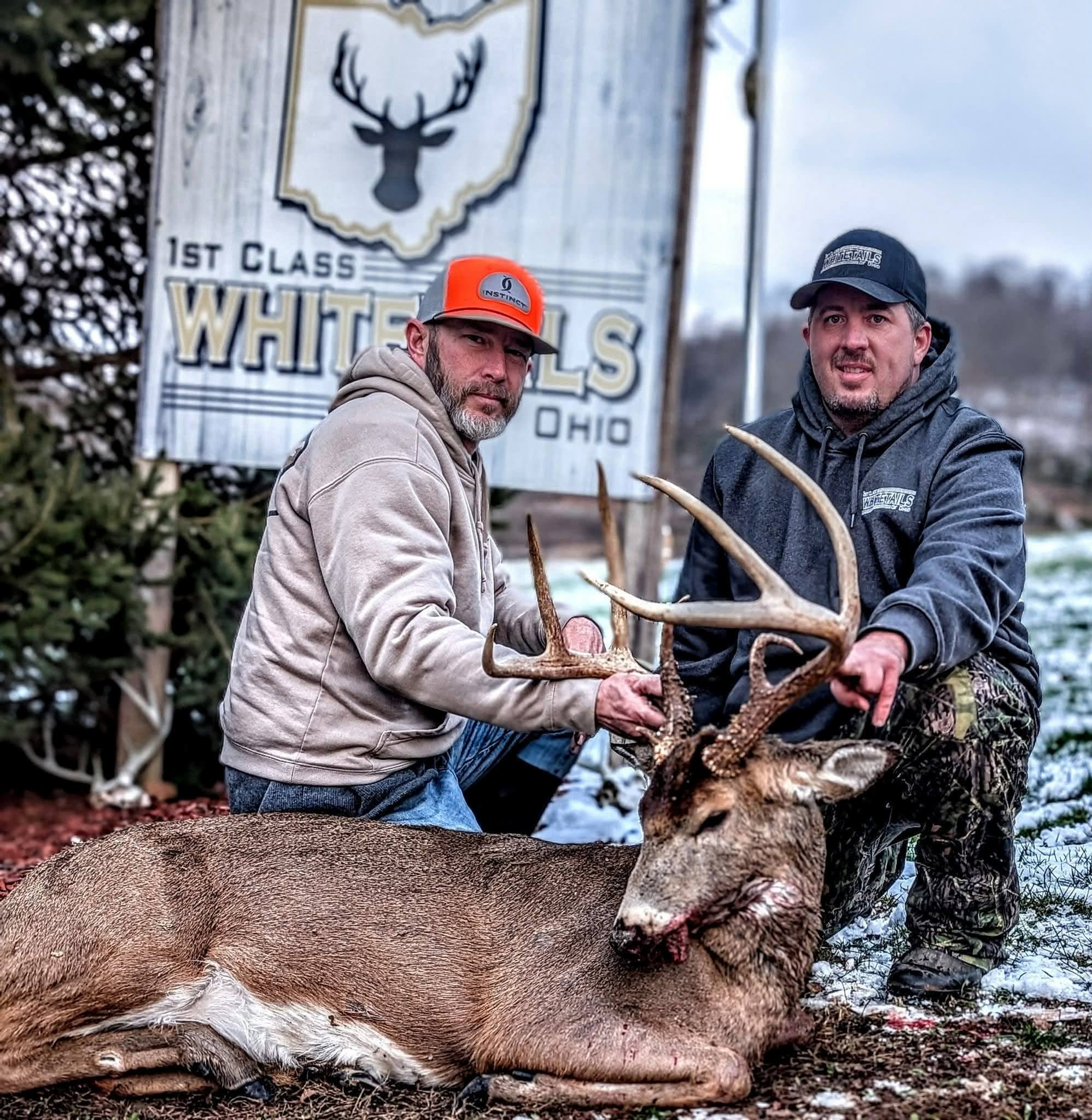 Two hunters with a wide-racked Ohio buck on a snowy day